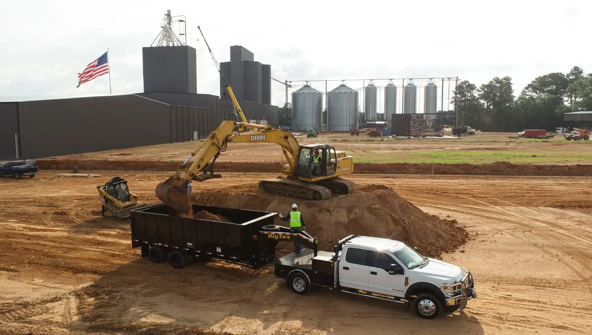 Big Tex 25DU gooseneck dump trailer being loaded by an excavator on a jobsite